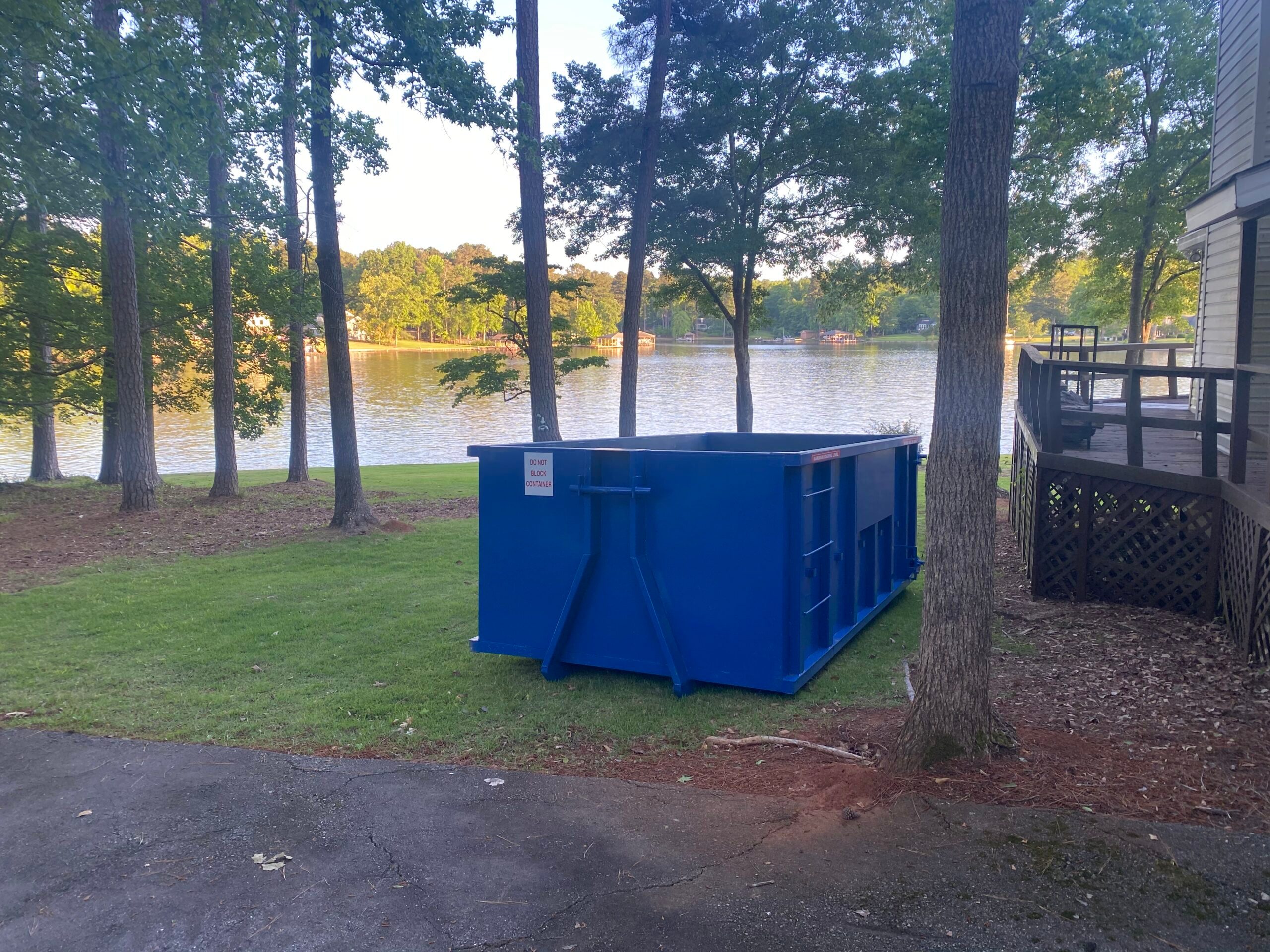 Blue roll-off dumpster on a lawn at a lakefront home