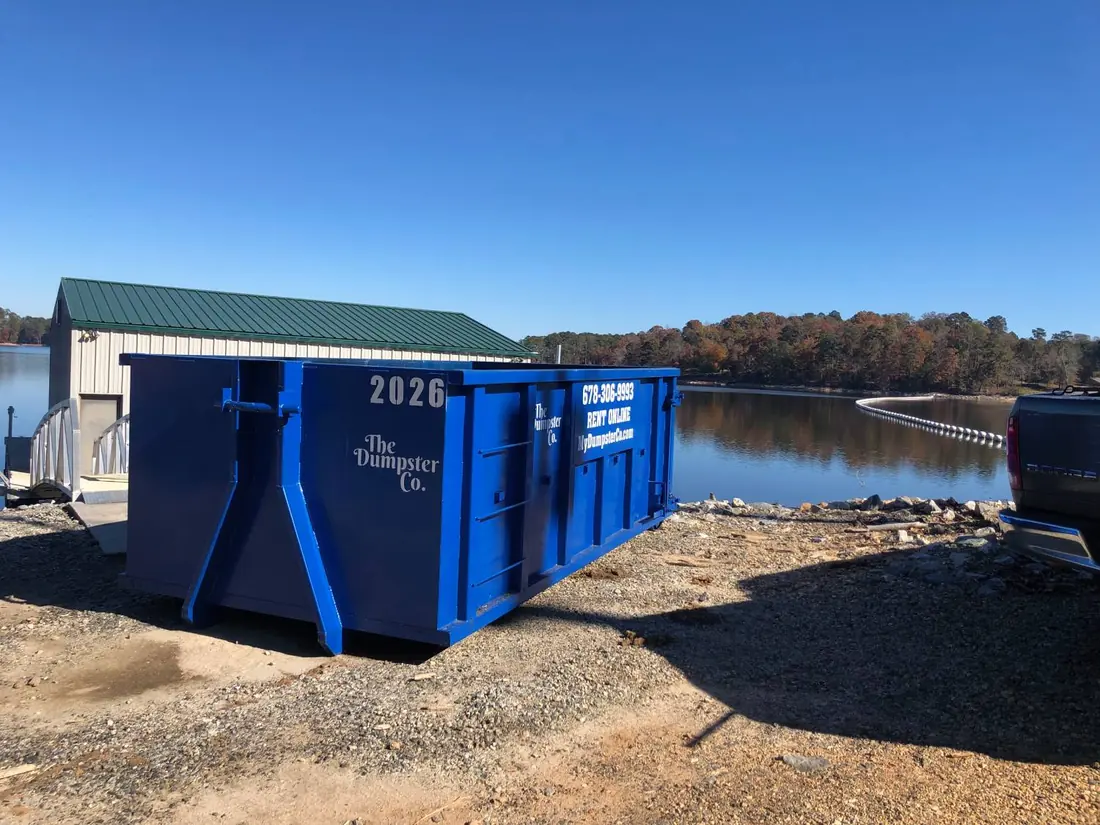 Blue roll-off dumpster delivered to a lakeside property