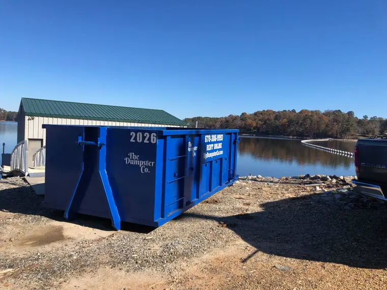 Blue roll-off dumpster delivered to a lakeside property