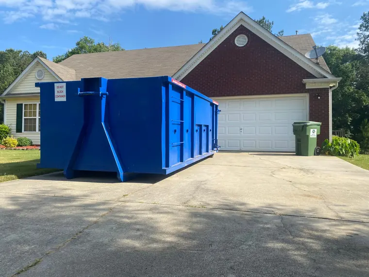 Blue roll-off dumpster in a residential driveway