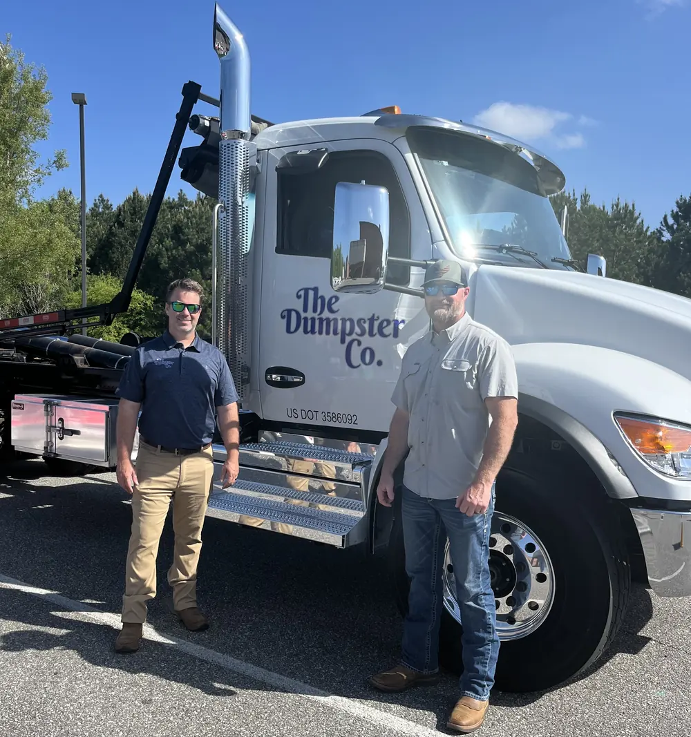 The Dumpster Co. team standing beside a company roll-off truck
