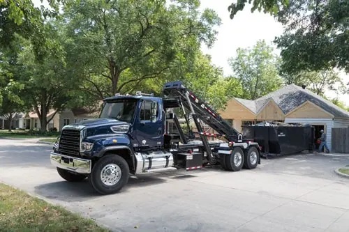 Freightliner 114SD roll-off truck delivering a dumpster in a residential neighborhood