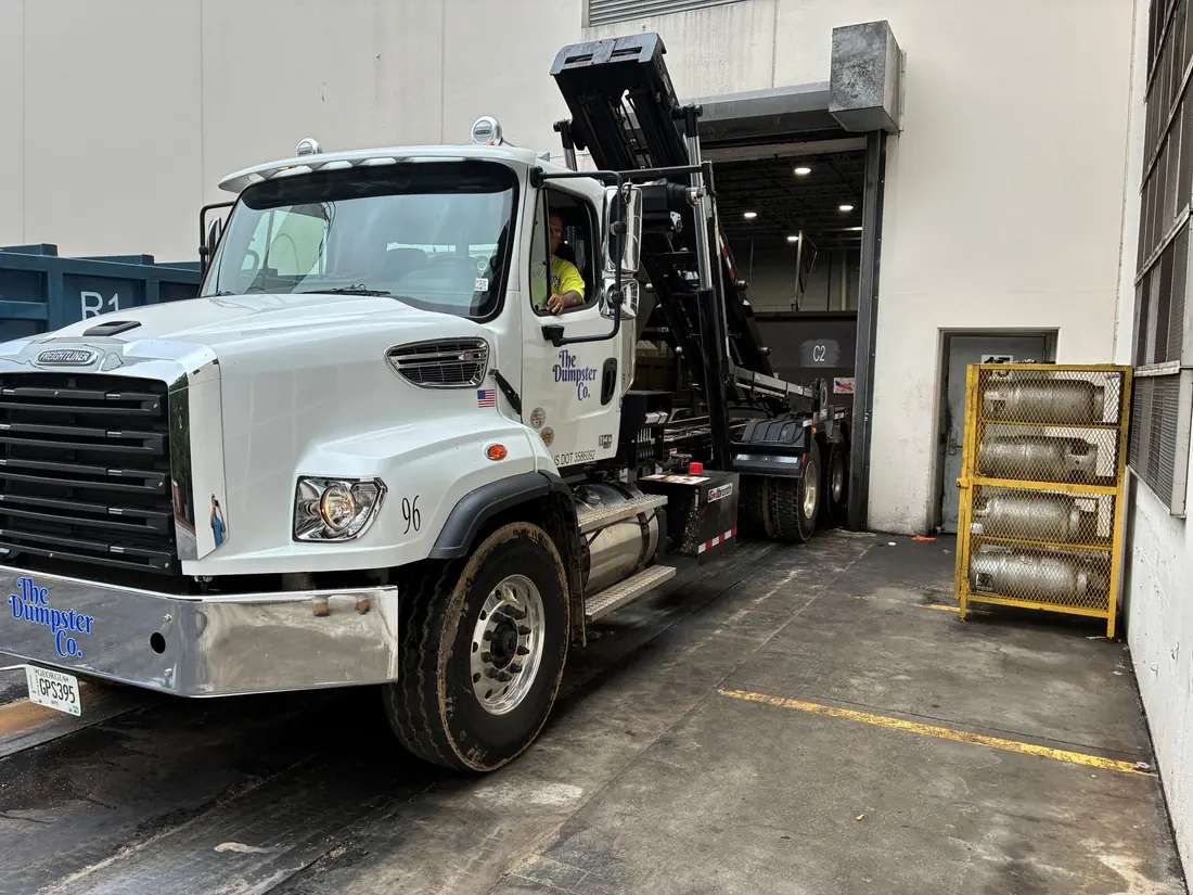 The Dumpster Co. roll-off truck at a commercial warehouse loading dock